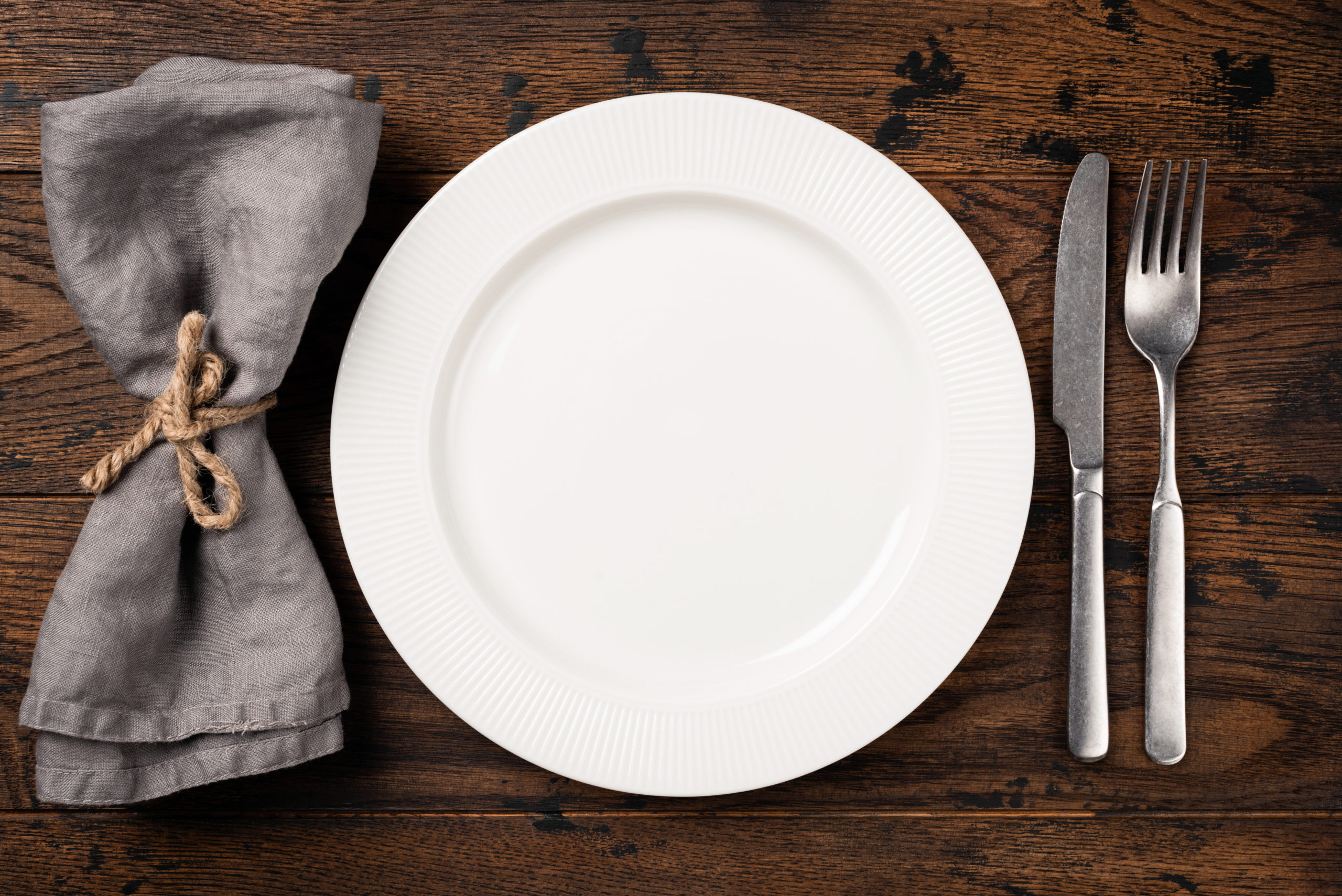 pöydällä kattaus, tyhjä lautanen, aterimet ja servetti